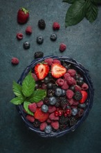 Mix of fresh berries, in a basket, on a wooden gray table, no people, top view