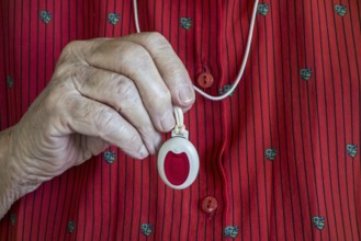 Close up of hand holding life-saving personal alarm for the elderly and disabled people showing