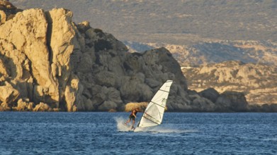 A windsurfer navigates past large rock formations, windsurfer, Meltemi windsurfing spot, Devils