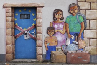 Refugee family standing in front of a closed door to Europe, mural on the subject of migration,