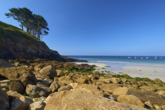 Rocky coastal landscape with sandy beach, boats on the sea in bright sunshine, Brittany, France,