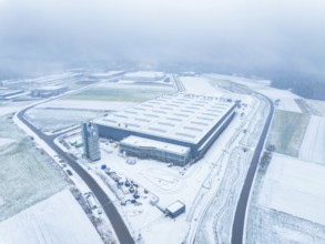 Aerial view of a modern industrial complex, surrounded by snow-covered fields and roads, barren