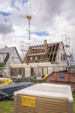 Renovation work with exposed roof truss, scaffolding and crane above a house