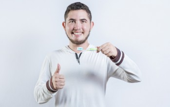 Happy man showing toothbrush with toothpaste gesturing OK. Handsome man holding brush with OK