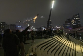 Person launches firework rocket from his hand, New Year's Eve 2025 on the Elbe promenade in