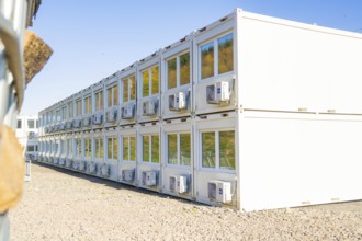 White containers with rows of windows and air conditioning units, reflecting the surroundings,