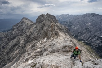 Mountaineer with helmet climbing on the rock, on a narrow rocky ridge, crossing the Jubiläumsgrat,