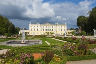 A magnificent baroque palace with manicured gardens and flowerbeds under a cloudy sky, Branicki