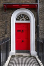 Red entrance door in a brick building with a cast-iron fence, Charles Dickens Museum, 48-49 Doughty