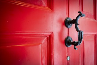 Close-up of a black door knocker on a red door, entrance to the Charles Dickens Museum, 48-49