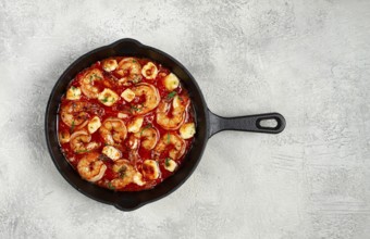 Greek saganaki, in an iron pan, saganaki with shrimp, shrimp in tomato sauce, with pepper and feta