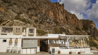 A restaurant in front of striking rocky cliffs with traditional stone architecture and wooden