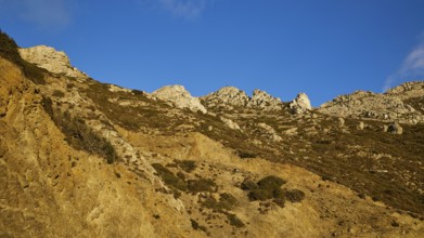 Steep rocks and dry landscape under a deep blue sky, morning light, sunrise, coastal road, east