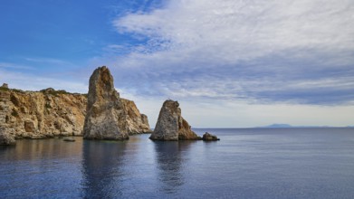 Jagged rocks rise from calm waters under a partly cloudy sky, boat tour Saria, Saria Island,