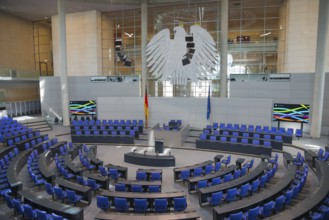 Symmetrical plenary chamber with blue chairs and large eagle as a central element, political