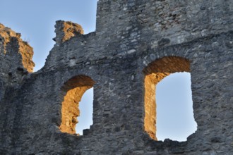 Old stone ruins with two window openings, illuminated by the warm light of the golden hour,