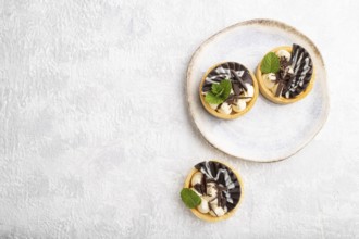 Sweet tartlets with chocolate and cheese cream on a gray concrete background. top view, flat lay,