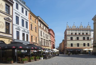 Town square with historic facades and street cafés under a blue sky, Chociszewska tenement house,