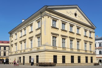 Historic yellow building with classical elements and rows of windows under a clear sky, registry