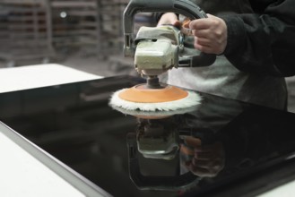 Worker Polishing black wood panel with grinder machine in production plant cropped shot