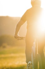 Silhouette of a cyclist in strong sunlight on a dirt track, e-bike, forest bike, Calw, district of