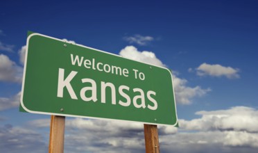 Welcome to kansas green road sign over blue sky with some clouds