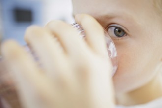 Symbolic photo on the subject of drinking water in high temperatures. A boy drinks a glass of water