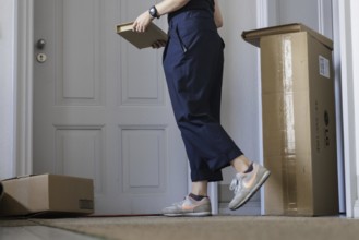 A woman leaves a parcel on her neighbour's doorstep in Berlin, 08.08.2024