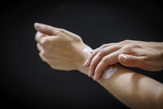 A person rubs a cream on her arm in Berlin, 09/08/2024