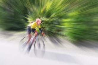 Cyclist in sportswear and helmet riding at high speed on a road, race, the motion blur emphasises