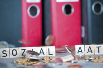 Wooden letters show the word SOCIAL STATE, falling coins knock over the letters (symbolic image)