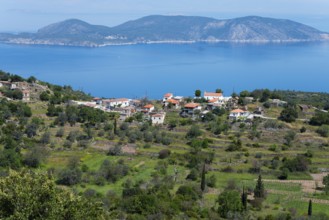 Coastal landscape with traditional houses and hills surrounded by blue sea and green vegetation,