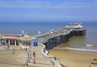 Sunny summer day sea beach and pier at Cromer, Norfolk, England, UK