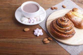 A cup of hot chocolate and buns on brown wooden background. close up, copy space