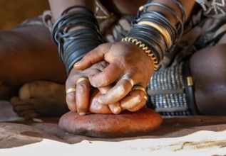 Hands of a woman with painting stone, Traditional Himba woman makes ochre colour for body painting