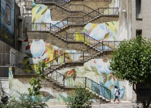 Passers-by walk up a staircase painted with roses in Tehran. The city of Tehran is changing the