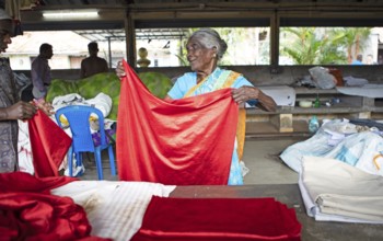 Indian woman folding laundry at Dhoby Khana laundry, Kochi, Kerala, India, Asia