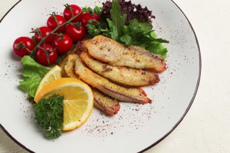 Fried Tilapia fish fillet, in spices, with cherry and salad, on a white plate, homemade, no people