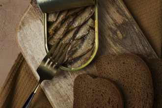 Sprats in butter, with black bread, canned smoked fish, open, close-up, top view, no people