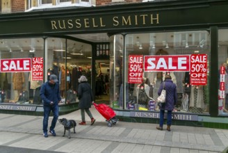 Sale poster signs in shop window of Russell Smith clothing store, Felixstowe, Suffolk, England, UK