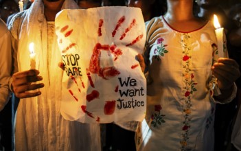 Students holds candle and shout slogans as they participate in a protest against the rape and