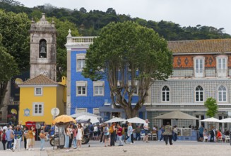 Lively square with people in front of colourful buildings and large trees, Praça da República,