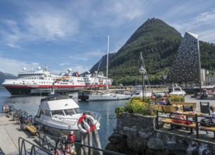 Andalsnes harbour, sailing boats and Hurtigruten ship anchor in the harbor on a sunny summer day.