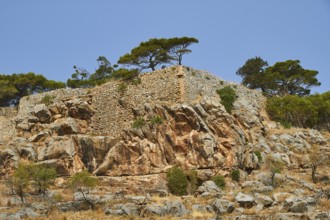 Rocky landscape with ancient wall remains surrounded by trees under a clear sky, Venetian Sea