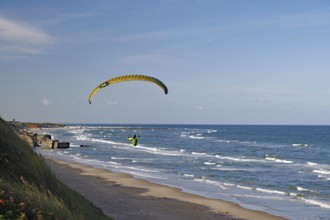 Paraglider soaring over the beach along the coastline with a view of the sea and the waves, Sport,