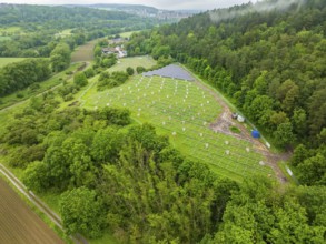 Aerial view of solar installations in a green landscape, surrounded by forest and fields,