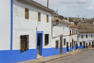 Rustic village with blue and white painted houses along a quiet street, Campo de Criptana, Ciudad