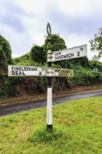 Old moss-covered signposts in the countryside, showing direction and distance to Ham, Sandwich and