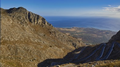 Serpentine road winds through a dry mountainous landscape down to the sea, Kallikratis, Kallikratis