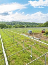 Metal frames of a solar park under construction in a rural area, surrounded by forests and under a